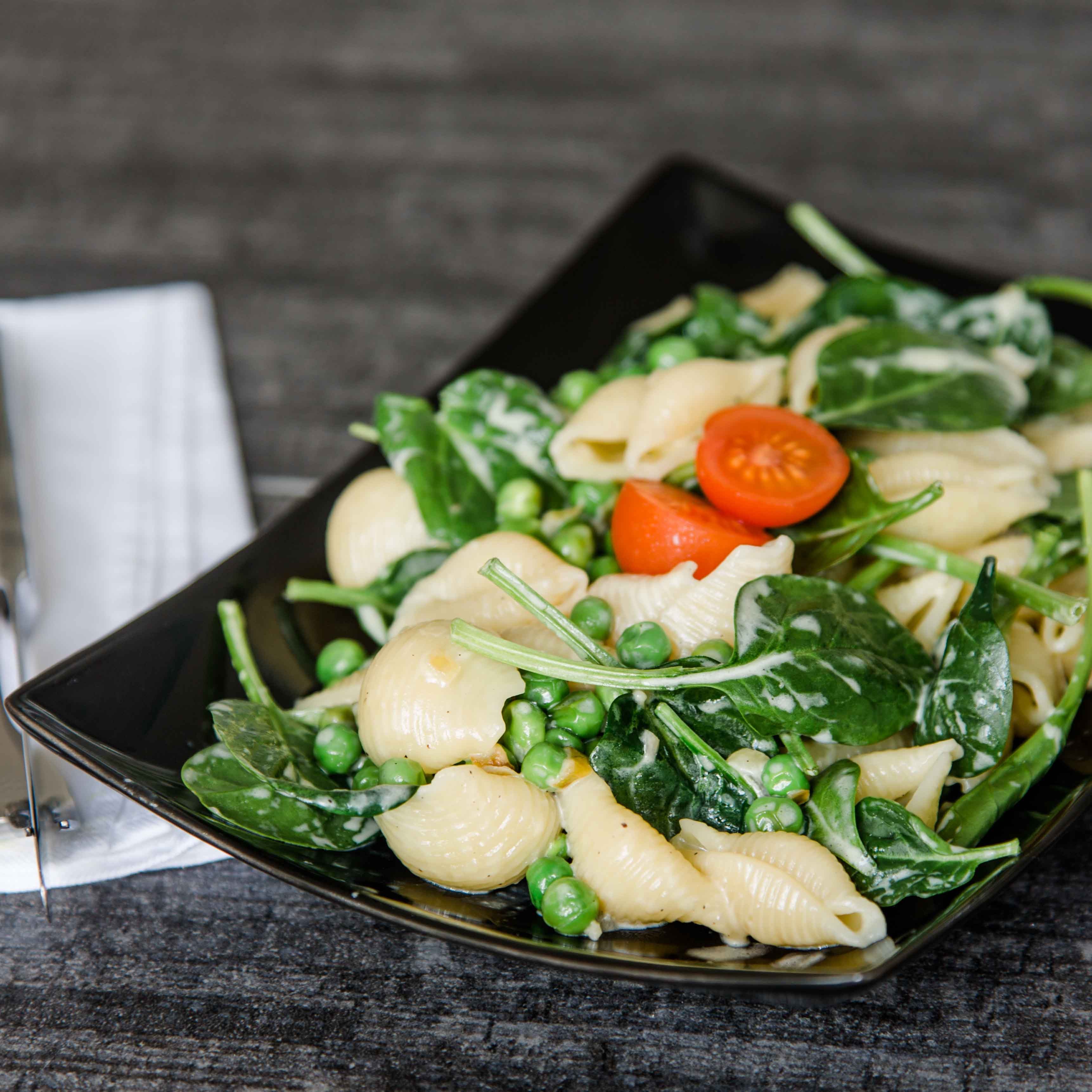 Pasta mit feiner Parmesansauce, Erbsen, jungem Spinat und frischen Kräutern