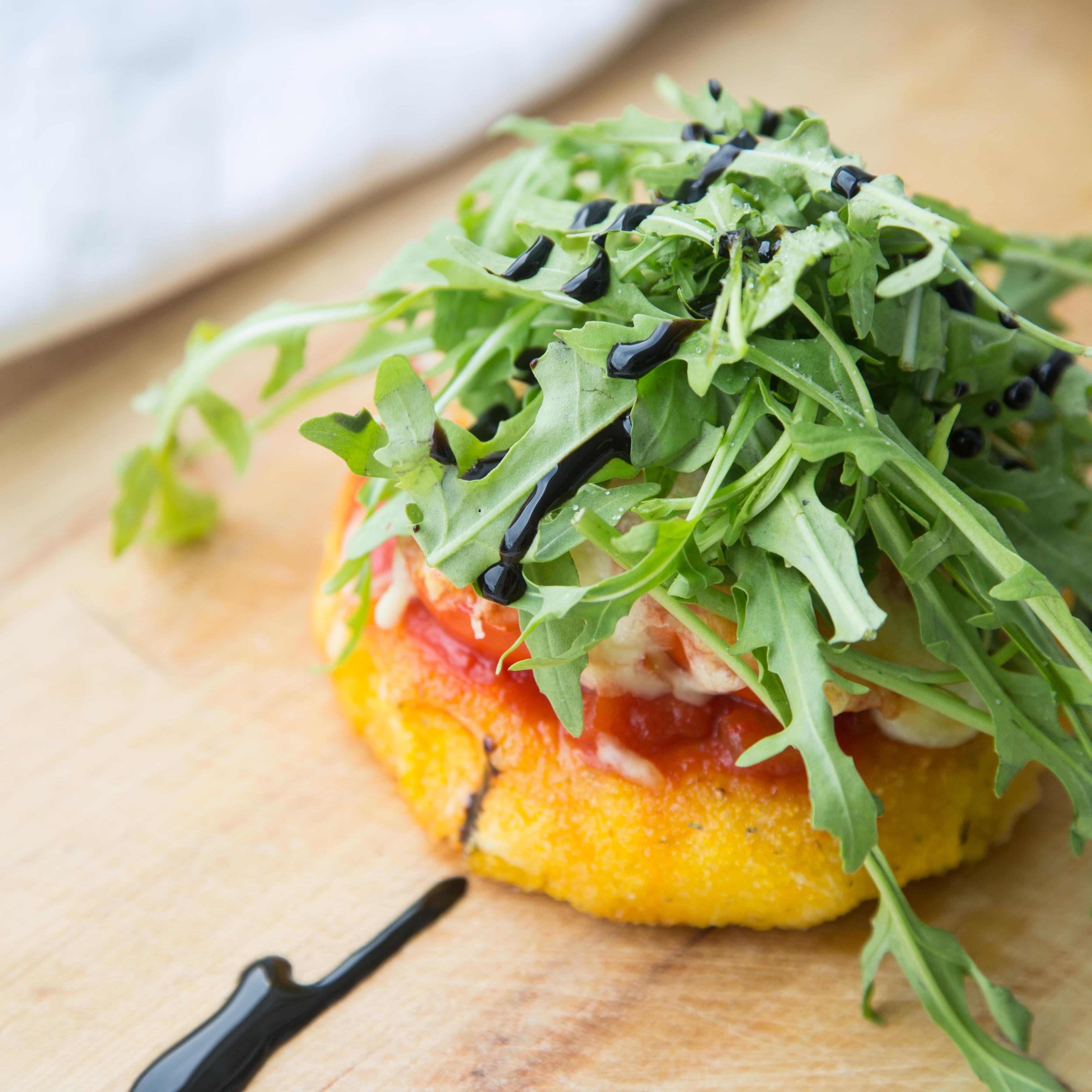 Gebratene Polenta mit Tomaten und Käse überbacken, mit Rucola garniert